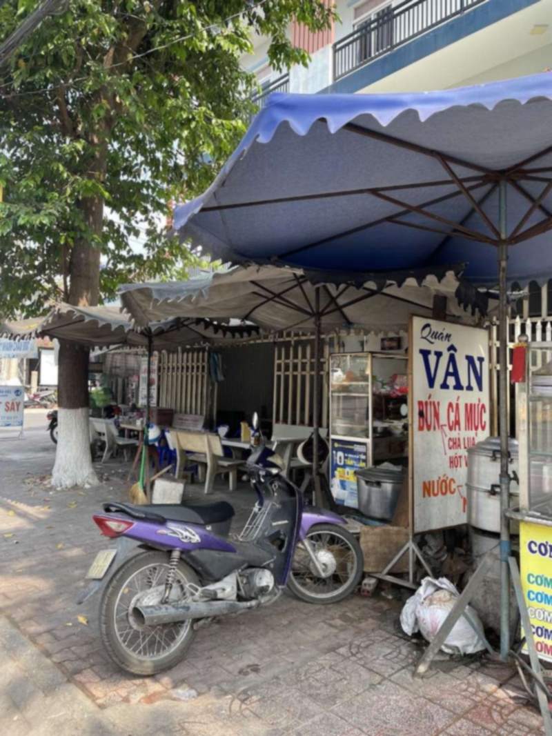 Quán Vân bên vỉa hè với bảng hiệu bún cá mực dưới dù xanh