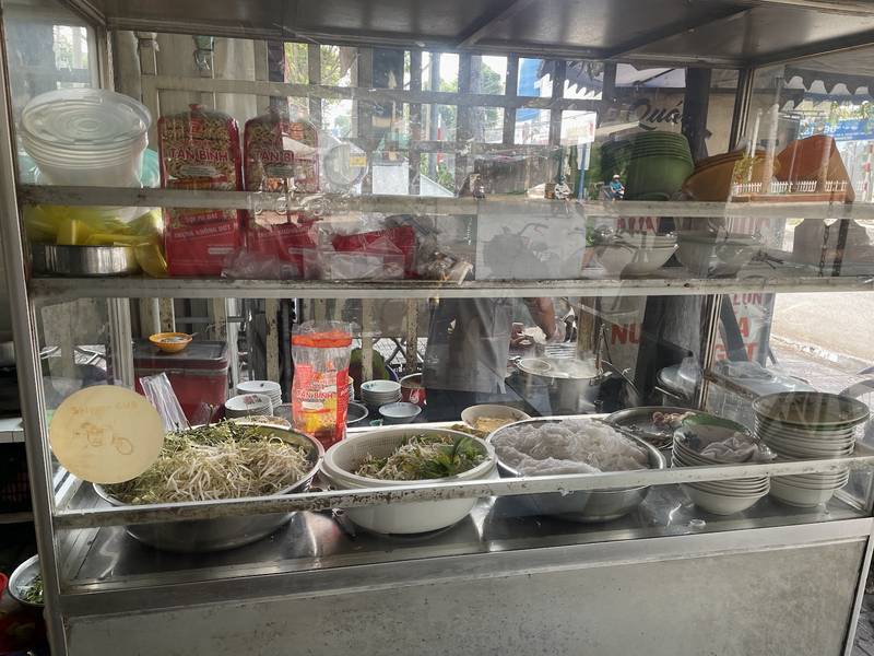 Xe bún cá Vân với rổ rau, bún và chồng tô bên đường Phan Đình Phùng